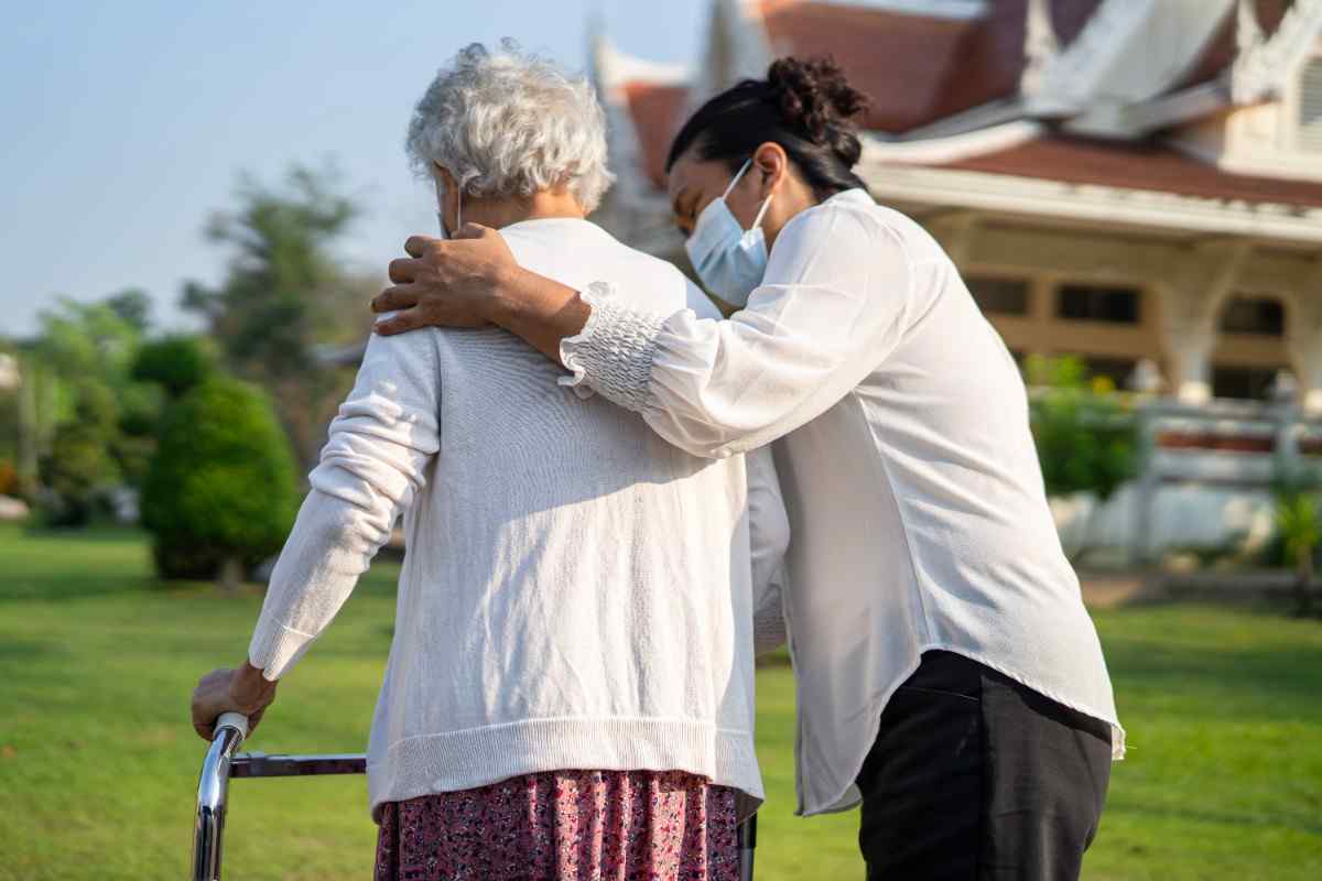 The image shows the care assistant, help the patient to walk